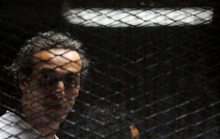 Egyptian photojournalist Mahmoud Abou Zeid, also known as Shawkan, looks on behind bars in his trial on the outskirts of Cairo, Egypt, on May 31, 2016. Shawkan was sentenced to five years in prison on September 8, 2018. (Reuters/Amr Abdallah Dalsh)