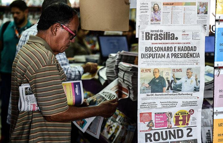 Homem em uma banca em Brasília, em 8 de outubro, lê sobre o primeiro turno das eleições no Brasil. O CPJ e outros grupos de direitos humanos estão pedindo aos candidatos que denunciem ameaças à imprensa. (AFP / Evaristo SA)