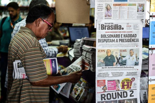 A man at a news kiosk in Brasilia on October 8 reads about the first round of Brazil's elections. CPJ and other rights groups are calling on candidates to denounce threats being made toward the press. (AFP/Evaristo SA)