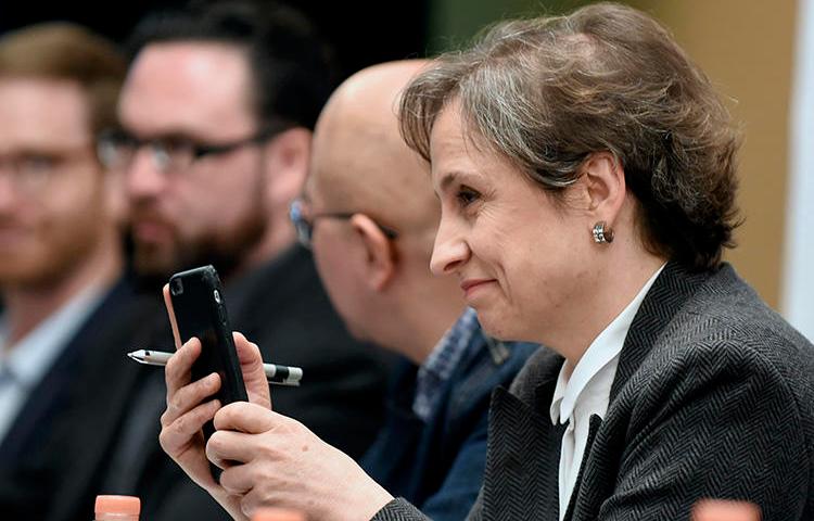 A jornalista mexicana Carmen Aristegui segura seu celular durante uma coletiva de imprensa na Cidade do México em 2017 sobre os governos que usam spyware para atacar jornalistas. (AFP/Alfredo Estrella)