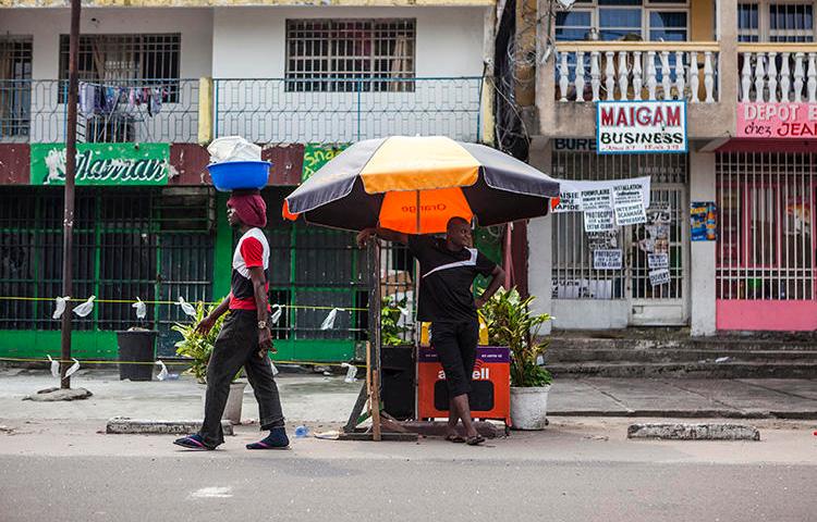 A man stands by a street stall as another one walks past him in Kinshasa, Democratic Republic of the Congo, on December 21, 2016. A newspaper editor was detained for criminal defamation in Kinshasa on October 10, 2018. (AFP/Eduardo Soteras)