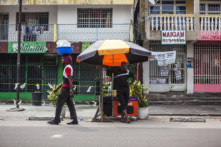 A man stands by a street stall as another one walks past him in Kinshasa, Democratic Republic of the Congo, on December 21, 2016. A newspaper editor was detained for criminal defamation in Kinshasa on October 10, 2018. (AFP/Eduardo Soteras)