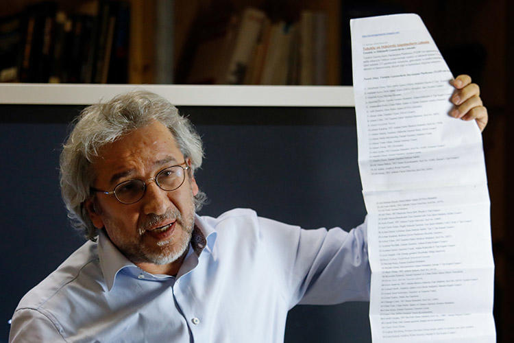 Exiled journalist Can Dündar holds up a list of journalists jailed in Turkey, during a September 28 press conference in Berlin. Prosecutors have asked for Interpol to issue a warrant for Dündar's arrest. (AFP/David Gannon)