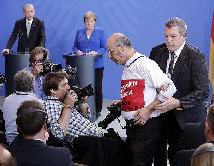 A Turkish man in a 'freedom for journalists' T-shirt is thrown out of a press conference for Turkey's President Recep Tayyip Erdoğan and German Chancellor Angela Merkel in Berlin on September 28. (AP/Michael Sohn)