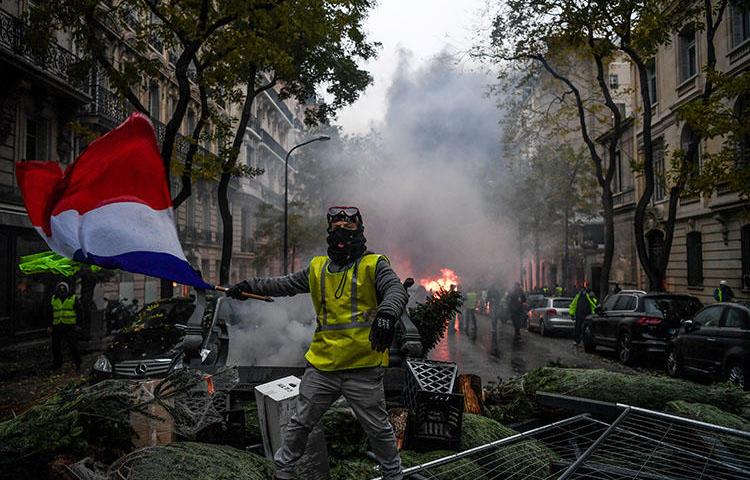 Un manifestant brandit le drapeau français lors d'un rassemblement à Paris le 1er décembre contre une proposition de hausse de la taxe sur le carburant. Les journalistes qui couvrent les troubles en France et en Belgique risquent d'être attaqués et blessés. (AFP/Alain Jocard)