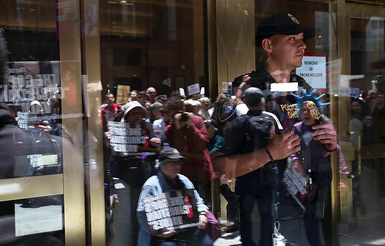 An ICE agent monitors a protest outside the department's office in San Francisco in June over President Trump's immigration policy. Journalists who fled threats in their home countries are being held in prolonged ICE detention while authorities review their asylum requests. (Getty Images North America/AFP/Justin Sullivan)