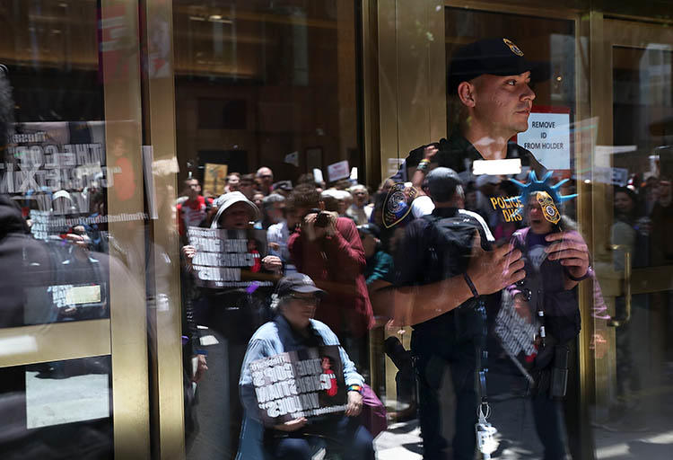 An ICE agent monitors a protest outside the department's office in San Francisco in June over President Trump's immigration policy. Journalists who fled threats in their home countries are being held in prolonged ICE detention while authorities review their asylum requests. (Getty Images North America/AFP/Justin Sullivan)