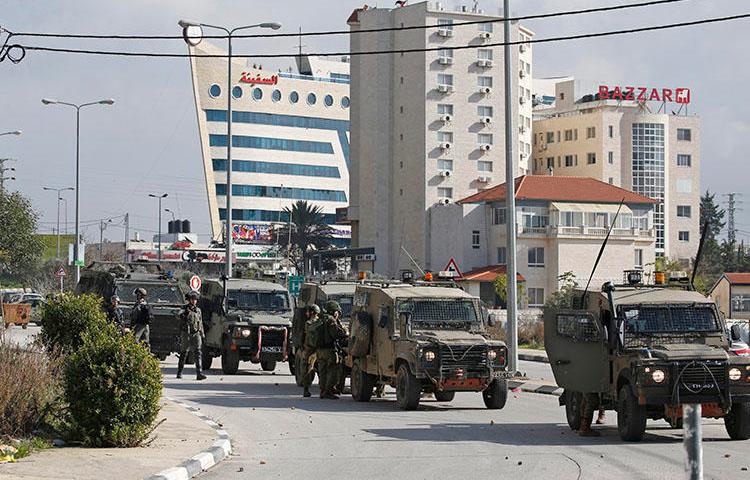 Israeli soldiers deploy during clashes in the West Bank city of Ramallah following a raid on December 10, 2018, one day after a drive-by shooting attack next to a settlement in which many Israelis were injured. Israeli forces raided the offices of the official Palestinian news agency, and detained a Palestinian journalist. (AFP/Abbas Momani)