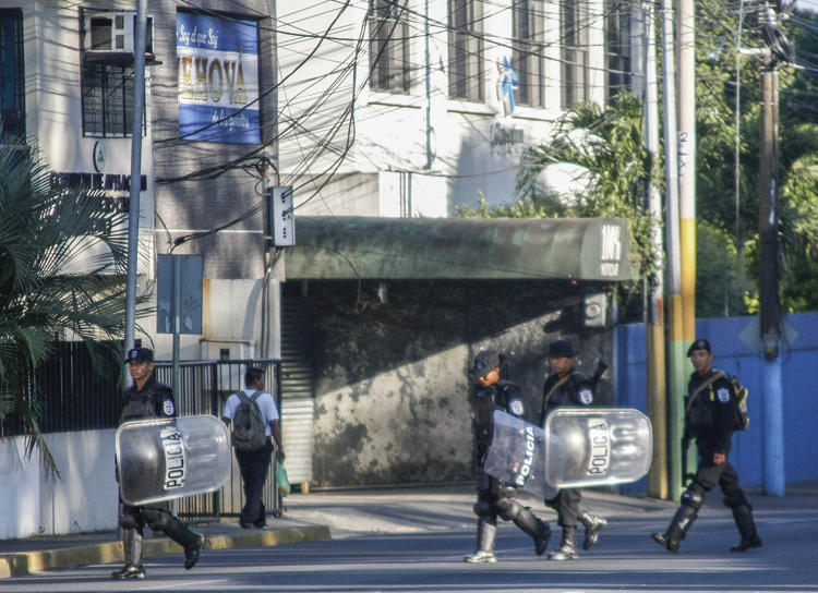 Riot police walk in front of the 100% Noticias cable and internet news station in Managua on December 22, 2018, a day after the station was raided and closed by the Nicaraguan police. Two journalists were arrested during the raid. (AFP/Maynor Valenzuela)