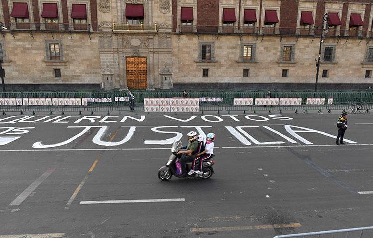 A police officer stands guard after members of the press wrote messages on the street during a protest against the murder or disappearance of more than 140 journalists in Mexico since 2000, in front of the National Palace in Mexico City on June 1, 2018. The body of journalist Alejandro Márquez Jiménez was found on December 1, 2018, near Tepic, the capital of the northwestern state of Nayarit. (AFP/Yuri Cortez)