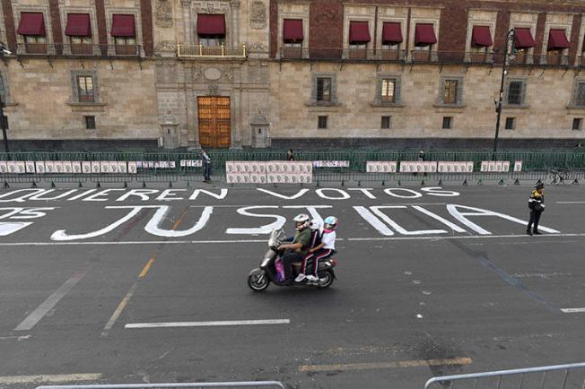 A police officer stands guard after members of the press wrote messages on the street during a protest against the murder or disappearance of more than 140 journalists in Mexico since 2000, in front of the National Palace in Mexico City on June 1, 2018. The body of journalist Alejandro Márquez Jiménez was found on December 1, 2018, near Tepic, the capital of the northwestern state of Nayarit. (AFP/Yuri Cortez)