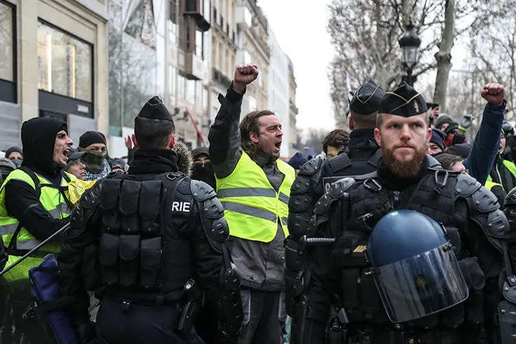 A protester raises his fist in front of security forces during a demonstration in Paris on December 15, 2018, to protest rising costs of living and high taxes. Dozens of journalists have been attacked and some injured by both protesters and police. (Zakaria Abdelkafi/AFP)