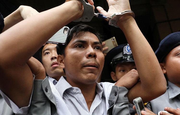 Agentes policiales se llevan esposado a Kyaw Soe Oo, periodista de Reuters, de un tribunal de Yangón en septiembre. Él y su colega Wa Lone cumplen una pena de siete años de cárcel en Myanmar. (Reuters/Ann Wang)