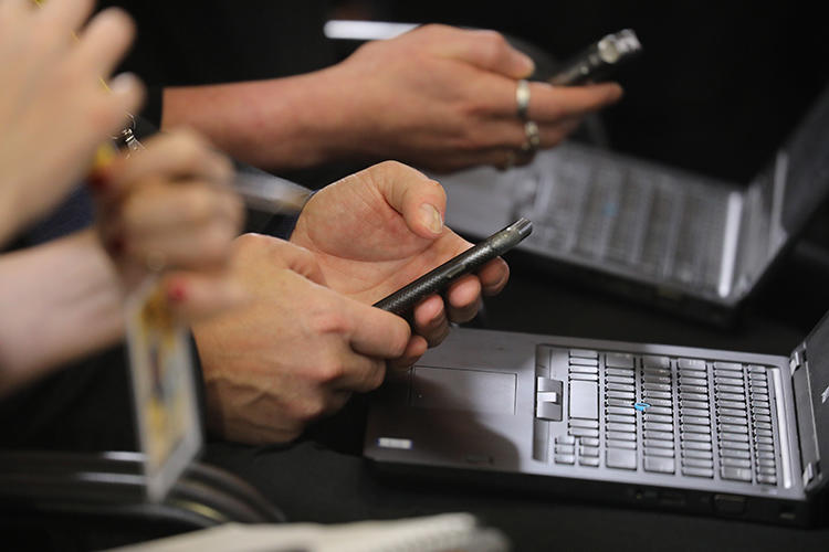 Jornalistas trabalham em seus telefones e laptops durante uma coletiva de imprensa em Bruxelas, em dezembro. Os hackers estão usando métodos sofisticados de phishing para tentar acessar as contas de repórteres e defensores dos direitos humanos (AFP/Ludovic Marin)