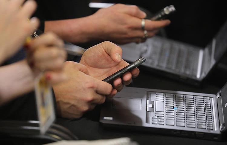 Journalists work on their phones and laptops during a press conference in Brussels in December. Hackers are using sophisticated phishing methods to try to access the accounts of reporters and human rights defenders. (AFP/Ludovic Marin)