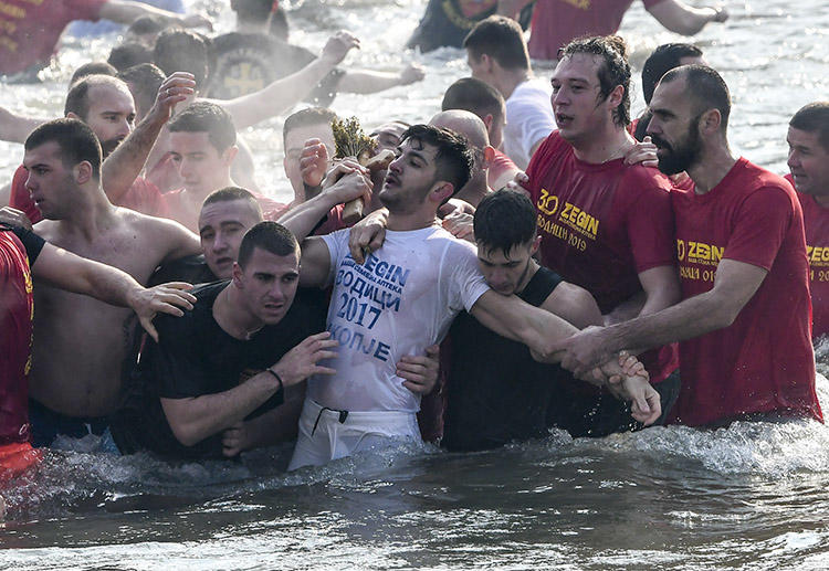 Participants in a religious event pull a cross out of the river Vardar in Skopje during Epiphany on January 19. A journalist covering the event says a security guard attacked her when she tried to interview one of the people taking part. (AFP/Robert Atanasovski)
