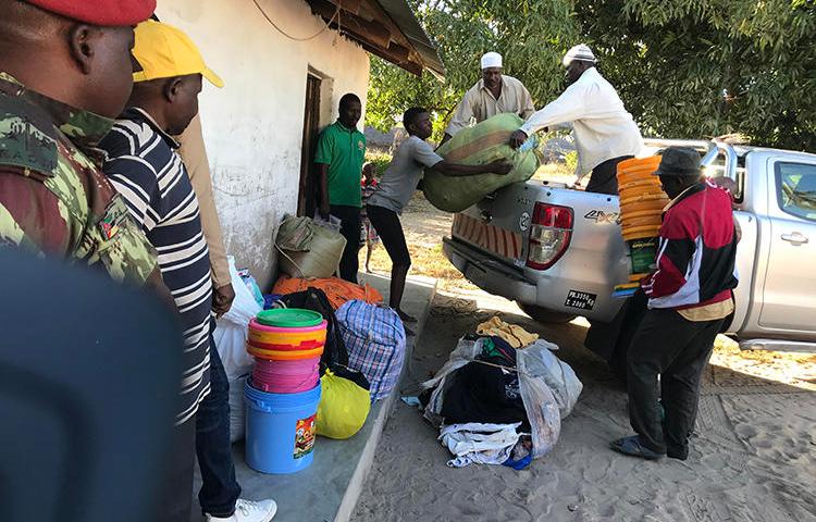 Internally displaced people offload food, blankets, and other goods after fleeing militant attacks in Naunde, northern Mozambique, on June 13, 2018. A Mozambican journalist was arrested on January 5, 2019, and held in a military prison after photographing families who fled the militant attacks. (AFP/Joaquim Nhamirre)