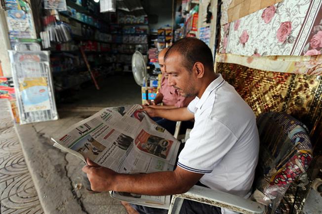 A Palestinian man reads a newspaper outside his store in Gaza City. The executive director of the Palestinian Journalists' Syndicate was recently detained and beaten by security forces in Gaza.