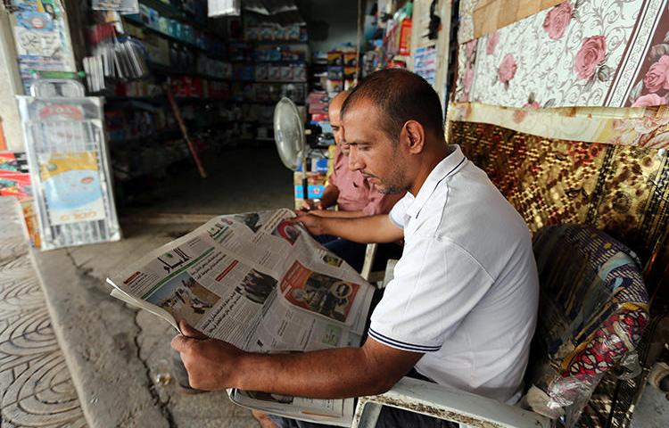 A Palestinian man reads a newspaper outside his store in Gaza City. The executive director of the Palestinian Journalists' Syndicate was recently detained and beaten by security forces in Gaza.