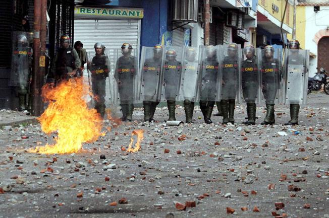 Fuerzas de seguridad observan durante choques en una manifestación en Venezuela el 24 de enero. En medio de la crisis política y manifestaciones en todo el país, las autoridades Venezolanas han allanado medios, detenido a periodistas y confiscado equipos. (Reuters/Carlos Eduardo Ramirez)