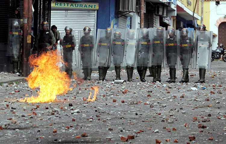 Forças de segurança observam os confrontos durante manifestação na Venezuela em 24 de janeiro. Em meio à crise política e aos protestos generalizados, as autoridades venezuelanas invadiram meios de comunicação, prenderam jornalistas e confiscaram equipamentos. (Reuters / Carlos Eduardo Ramirez)