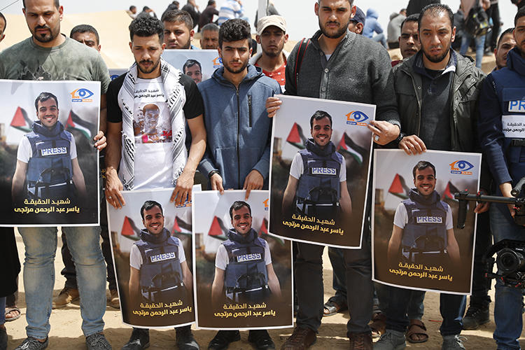 Palestinians hold portraits of reporter Yasser Murtaja on April 13, 2018. A UN commission recently stated that Murtaja and fellow Palestinian journalist Ahmed Abu Hussein were 'intentionally shot' by Israeli snipers. (Thomas Coex/AFP)