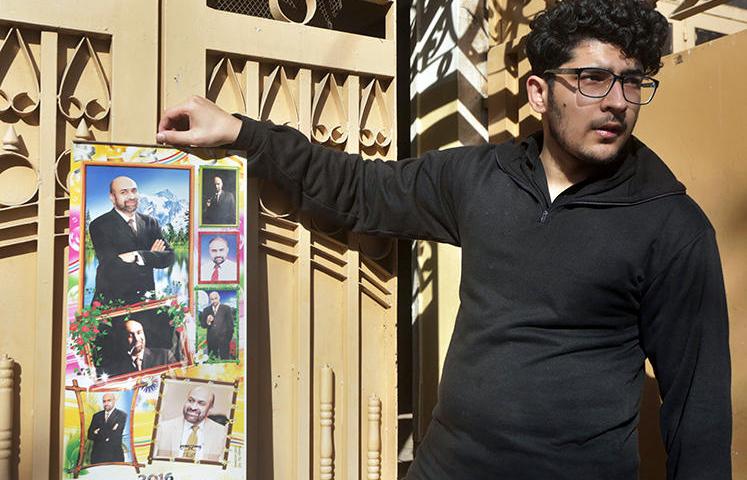 Osama Rizi, son of journalist Rizwan-ur-Rehman Razi, displays a calendar with pictures of his father outside his residence in Lahore, Pakistan, Saturday, Feb. 9, 2019. Pakistani authorities detained Razi, who allegedly criticized state agencies on traditional and social media, officials said Saturday. (AP/K.M. Chaudary)