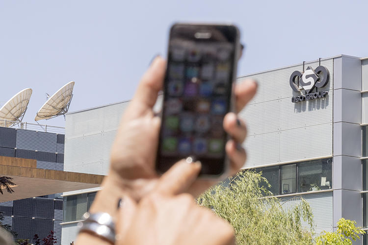 A woman uses her iPhone in front of the building housing NSO Group on August 28, 2016, in Herzliya, near Tel Aviv, Israel. The company has come under increased scrutiny for the alleged use of its spyware tool, Pegasus, to target journalists. (AFP/Jack Guez)