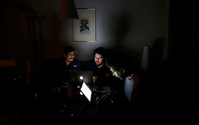 Fotojornalista trabalha em um quarto de hotel de Caracas durante o terceiro dia de uma queda de energia. Além do apagão, os jornalistas devem navegar pelos bloqueios da Internet impostos pelo governo de Nicolás Maduro, que tenta silenciar as notícias da oposição. (AFP/Juan Barreto)