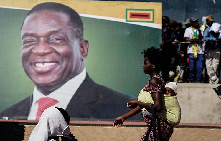 A woman walks in front of a picture of President Emmerson Mnangagwa in Bulawayo, in June 2018. Authorities in the Zimbabwean city detained documentary filmmaker Zenzele Ndebele on March 21. (AFP/Zinyange Auntony)