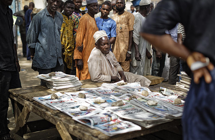 People gather around a newspaper stand in Kano, northern Nigeria, on February 24, 2019. Journalist Obinna Don Norman was recently charged under Nigeria's 2015 cybercrime act. (Ben Curtis/AP)
