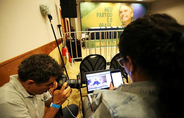Journalists follow a Facebook Live of Jair Bolsonaro, far-right lawmaker and presidential candidate of the Social Liberal Party (PSL), in Rio de Janeiro, Brazil, October 7, 2018. After taking office in January, Bolsonaro and his supporters have made Brazilian journalists' jobs more difficult. (Reuters/Sergio Moraes)