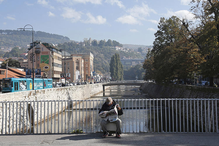 A man reads on a bridge in Sarajevo, Bosnia and Herzegovina, on October 6, 2018. A Sarajevo politician recently attacked a journalist in the city. (Amel Emric/AP)