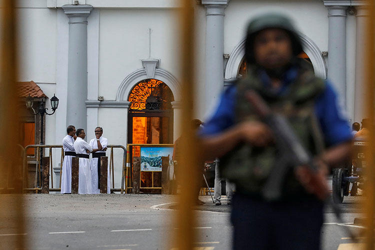 Priests are seen in the background as security personnel stand guard in front of St Anthony's shrine on April 29, 2019, days after a string of suicide bomb attacks across the island on Easter Sunday killed hundreds. (Reuters/Danish Siddiqui)