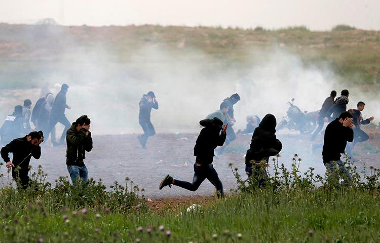 Palestinian protesters run for cover as Israeli forces fire tear gas canisters east of Gaza City on March 30, 2019. At least 10 journalists have been hurt by Israeli forces since late March. (AFP/Mahmud Hams)