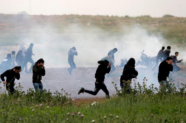 Palestinian protesters run for cover as Israeli forces fire tear gas canisters east of Gaza City on March 30, 2019. At least 10 journalists have been hurt by Israeli forces since late March. (AFP/Mahmud Hams)