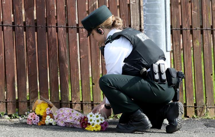 A police officer lays flowers passed to her by members of the public at the scene where journalist Lyra McKee was fatally shot amid rioting overnight in the Creggan area of Londonderry in Northern Ireland on April 19, 2019. (AFP/Paul Faith)