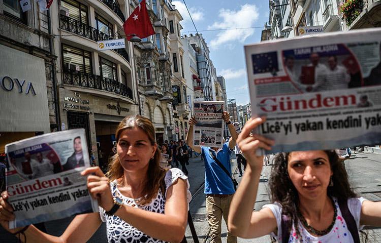 Protesters hold up copies of the pro-Kurdish daily Özgür Gündem during a rally in Istanbul in June 2016. Turkish courts will proceed with 14 cases against a former publisher of the now shuttered newspaper. (AFP/Oan Kose)