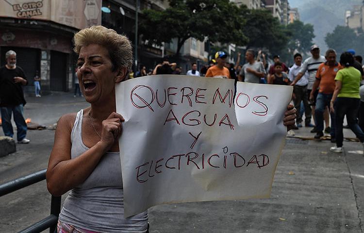 A woman holds a placard reading "We Want Water and Electricity" during a protest during a new power outage in Venezuela, at Fuerzas Armadas Avenue in Caracas on March 31, 2019. Venezuelan police detained reporter Danilo Gil while covering protests on March 30 in the town of Ciudad Ojeda, and charged him with resisting authority. (AFP/Federico Parra)