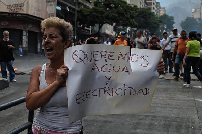 A woman holds a placard reading "We Want Water and Electricity" during a protest during a new power outage in Venezuela, at Fuerzas Armadas Avenue in Caracas on March 31, 2019. Venezuelan police detained reporter Danilo Gil while covering protests on March 30 in the town of Ciudad Ojeda, and charged him with resisting authority. (AFP/Federico Parra)