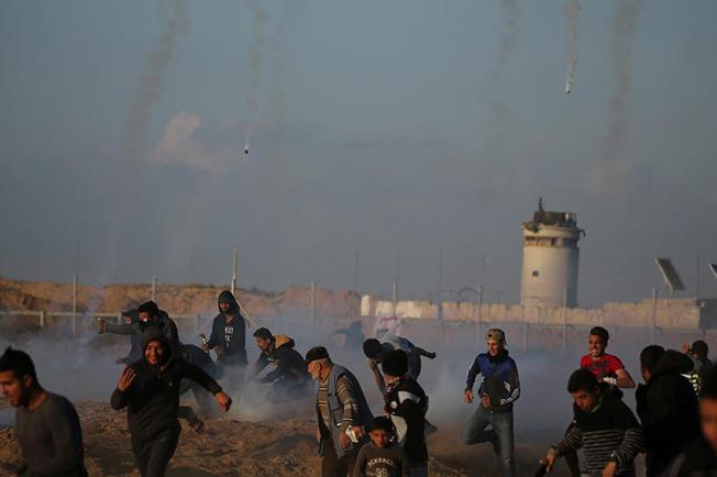 Demonstrators run as Israeli troops fire tear gas canisters in the southern Gaza Strip on April 19, 2019. At least four Palestinian journalists were injured by Israeli troops during the protests. (Reuters/Ibraheem Abu Mustafa)