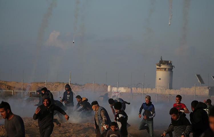 Demonstrators run as Israeli troops fire tear gas canisters in the southern Gaza Strip on April 19, 2019. At least four Palestinian journalists were injured by Israeli troops during the protests. (Reuters/Ibraheem Abu Mustafa)