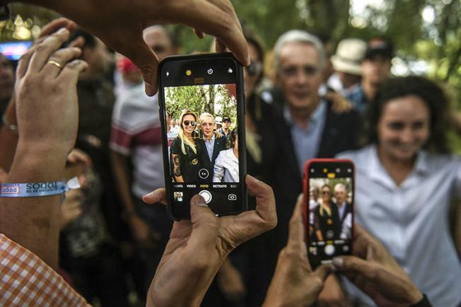 Álvaro Uribe, al centro, posa para fotografías con sus partidarios en su casa, en Rionegro, Colombia, en junio de 2018. El expresidente colombiano presentó una demanda civil por difamación en Estados Unidos contra el periodista Daniel Coronell. (AFP/Joaquín Sarmiento)