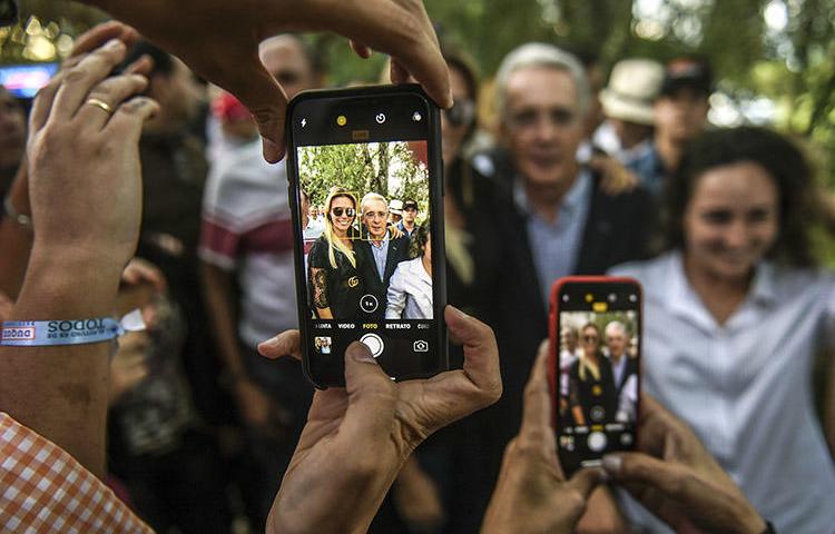 Álvaro Uribe, al centro, posa para fotografías con sus partidarios en su casa, en Rionegro, Colombia, en junio de 2018. El expresidente colombiano presentó una demanda civil por difamación en Estados Unidos contra el periodista Daniel Coronell. (AFP/Joaquín Sarmiento)