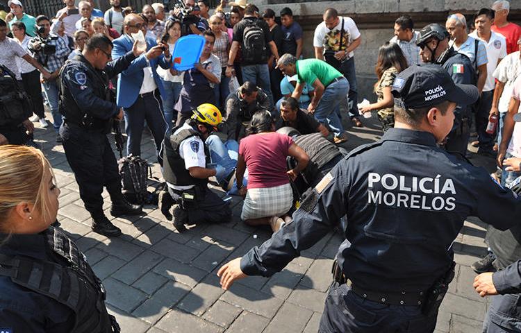 An injured man receives first aid after a gunman opened fire, killing two and injuring a journalist, in the central square of Cuernavaca, Morelos state, in Mexico on May 8, 2019. (AFP/STR)