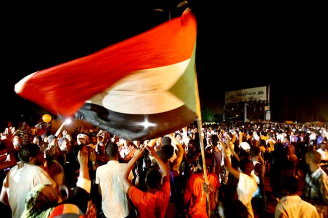 Sudanese wave flags and chant slogans as they gather outside the army headquarters in Khartoum on May 30. Sudan's military rulers have ordered Al-Jazeera's Khartoum bureau to be shut down. (AFP/Ashraf Shazly)