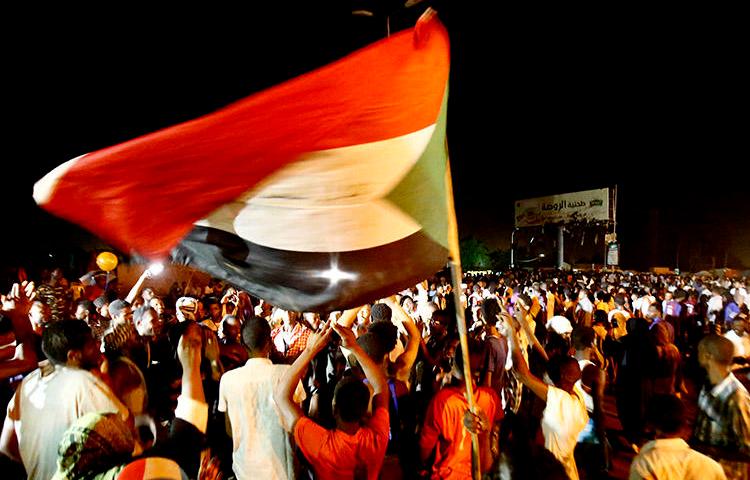 Sudanese wave flags and chant slogans as they gather outside the army headquarters in Khartoum on May 30. Sudan's military rulers have ordered Al-Jazeera's Khartoum bureau to be shut down. (AFP/Ashraf Shazly)
