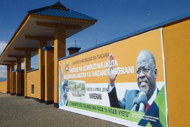 A banner of Tanzanian President John Magufuli hangs on a wall around a tanzanite mine, in April 2018. CPJ and other organizations are calling on the Human Rights Council to address a crackdown on journalists, human rights defenders, and other groups in the country. (AFP/Joseph Lyimo)