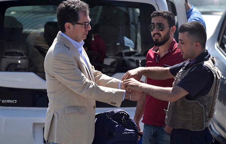 Kadri Gürsel, left, is handcuffed by police outside an Istanbul prison on May 29. Gürsel, a former columnist for Cumhuriyet, and Turkey chair of the International Press Institute, was freed later that day. (AP/DHA)