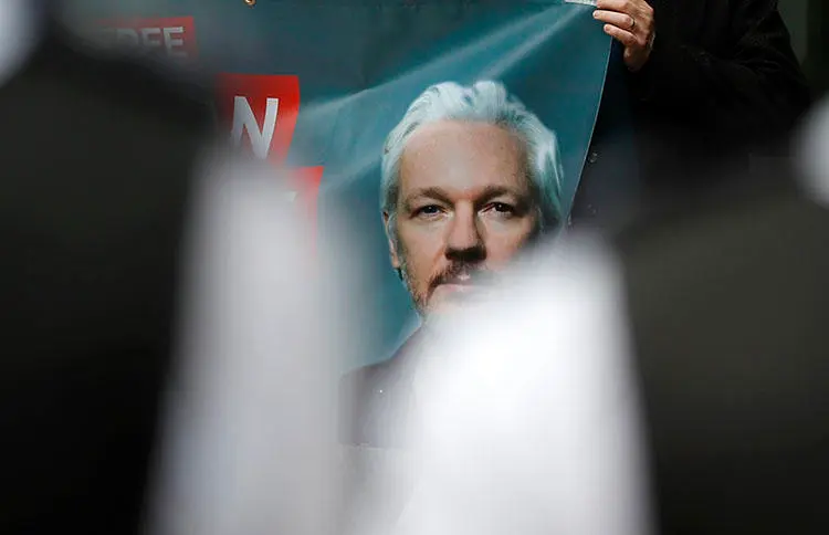 Police watch supporters of WikiLeaks founder Julian Assange protesting in London on June 14, 2019 before a scheduled court date in his fight against extradition to the United States, where he faces prosecution for conspiracy to commit computer intrusion, as well as the Espionage Act. (AP Photo/Frank Augstein)